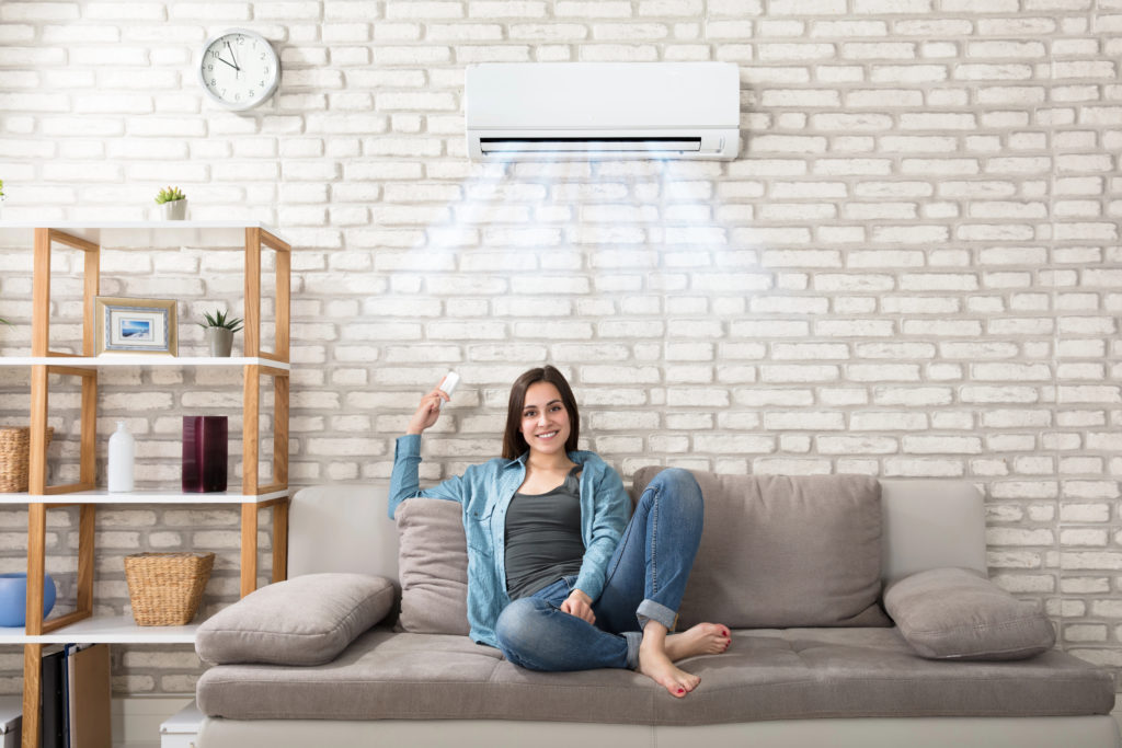 Femme souriante qui allume la climatisation